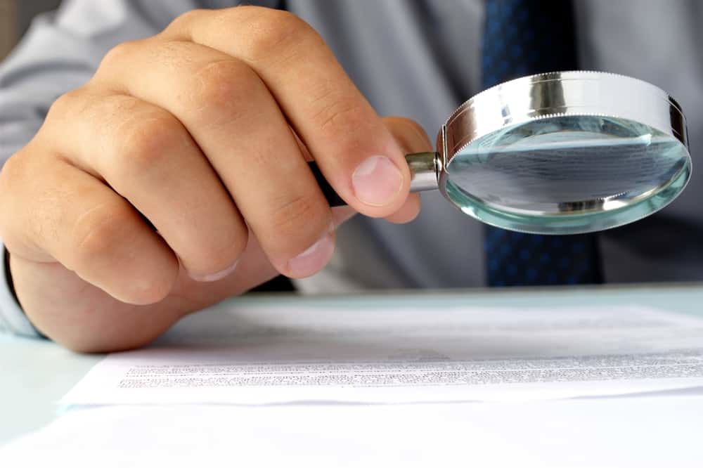 Businessman,Looking,Through,A,Magnifying,Glass,To,Documents
